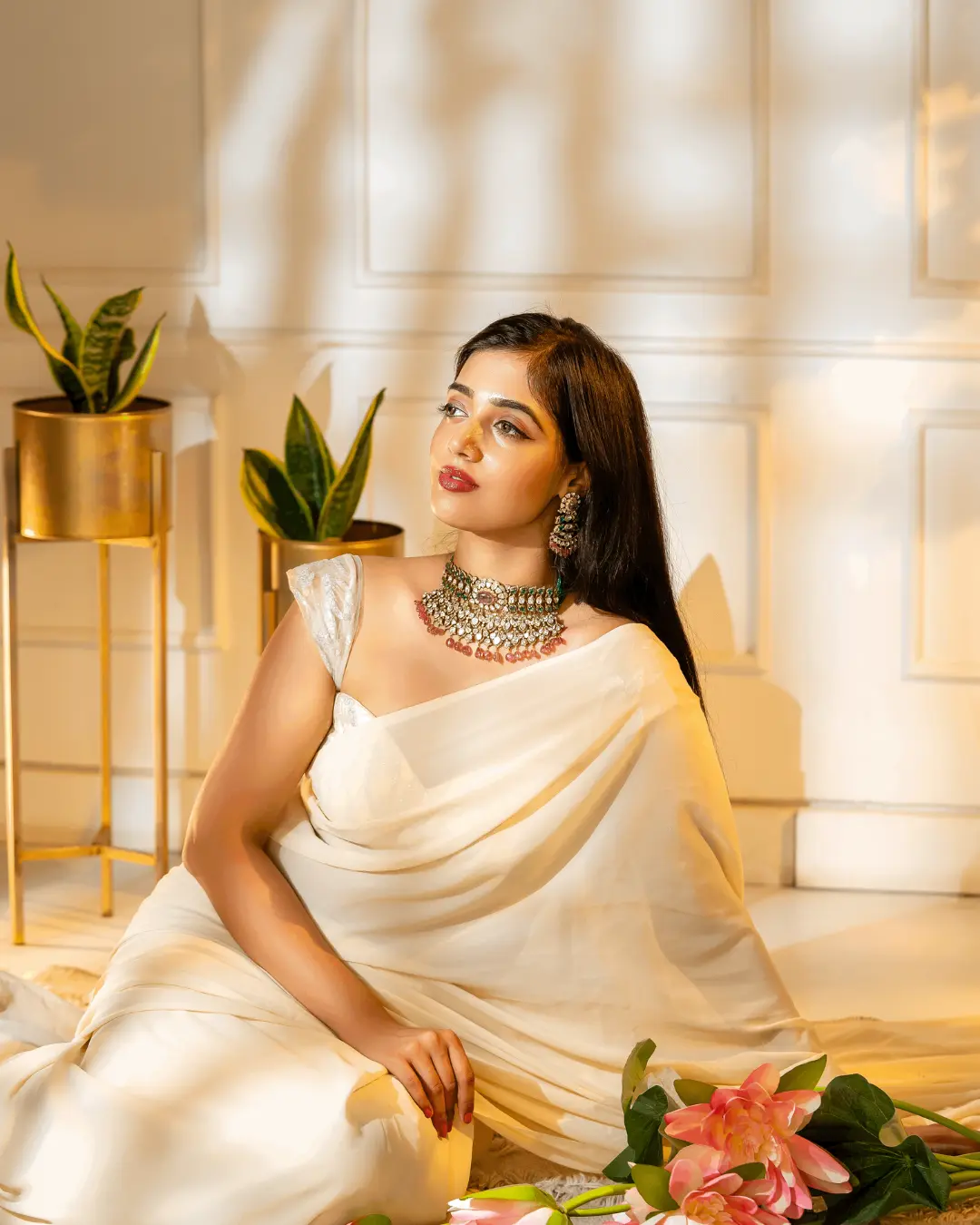 A woman sits gracefully on the floor in a cream-colored silk saree, a fashion stylist in Bangalore. Capturing these unscripted, golden-hour moments is where the magic of styling really comes to life.