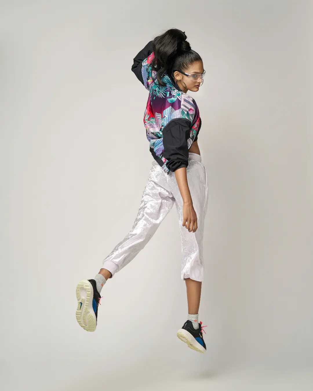 A female model captured in a mid-air jump against a light gray background. Styled by fashion stylist in Bangalore. The creative direction is as dynamic as the styling, every frame tells a story.
