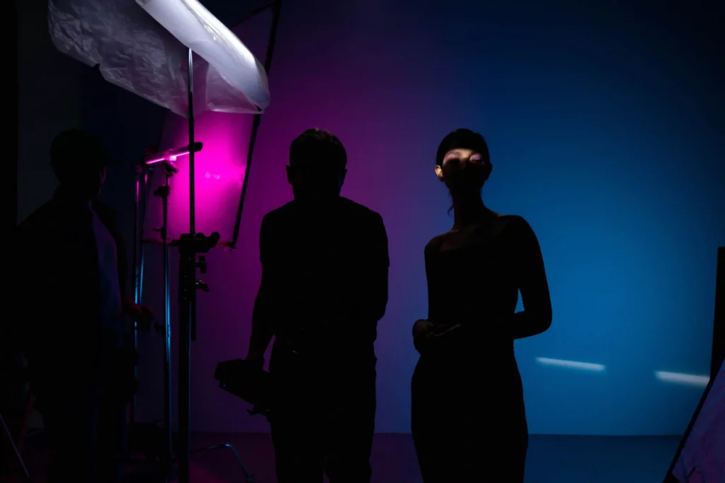 Behind-the-scenes of a high-fashion shoot led by a fashion stylist in Bangalore, featuring a model in silhouette with dramatic pink and blue studio lighting.